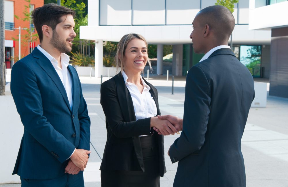 Business partners greeting each other outdoors. Business man and woman shaking hands. Partnership or deal concept